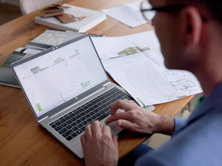 Architekt arbeitet am Laptop mit digitalen Bauplänen und Konstruktionsplänen.