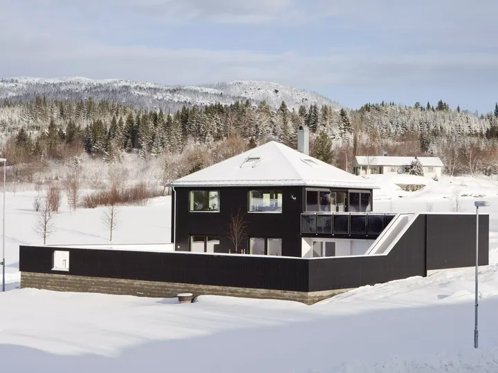 Bick auf schneebedecktes Haus mit Zeltdach und schwarzer Holzverkleidung | VELUX Magazin