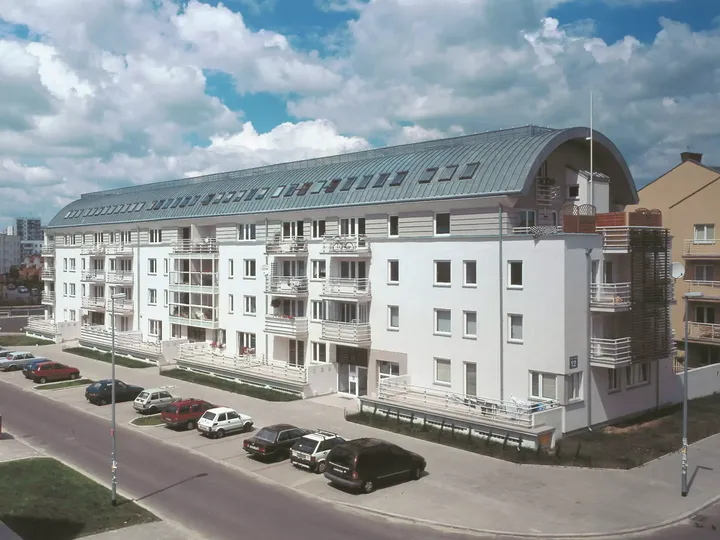 Modernes Apartmentgebäude mit VELUX Dachflächenfenstern und Balkonen unter einem klaren Himmel.