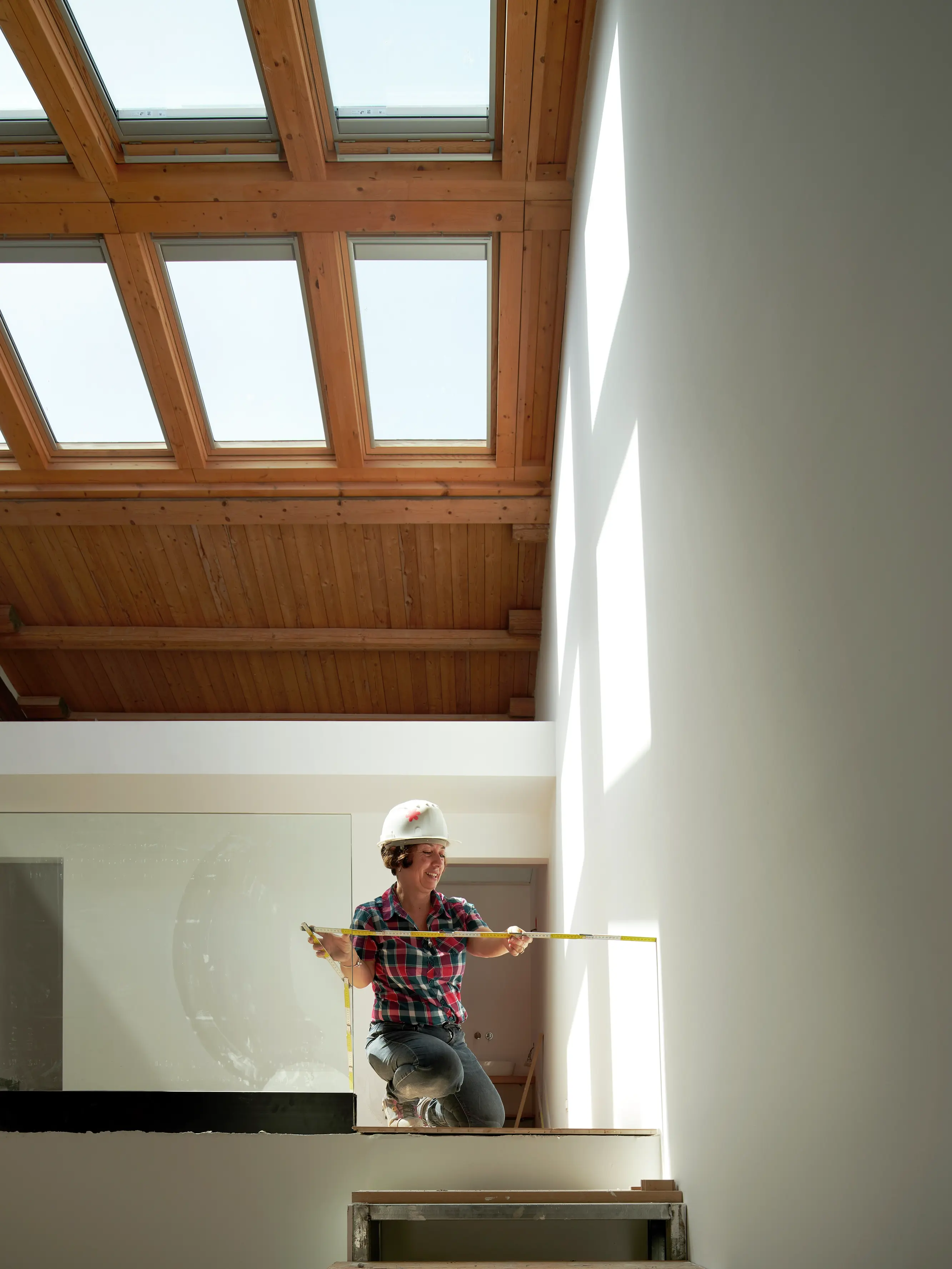 Persona che misura all'interno con luce naturale proveniente dalle finestre per tetti VELUX sopra.