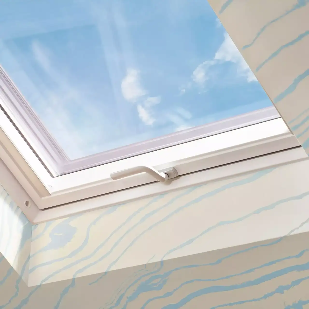 VELUX Dachflächenfenster an schräger Decke mit Aussicht auf blauen Himmel und Wolken.
