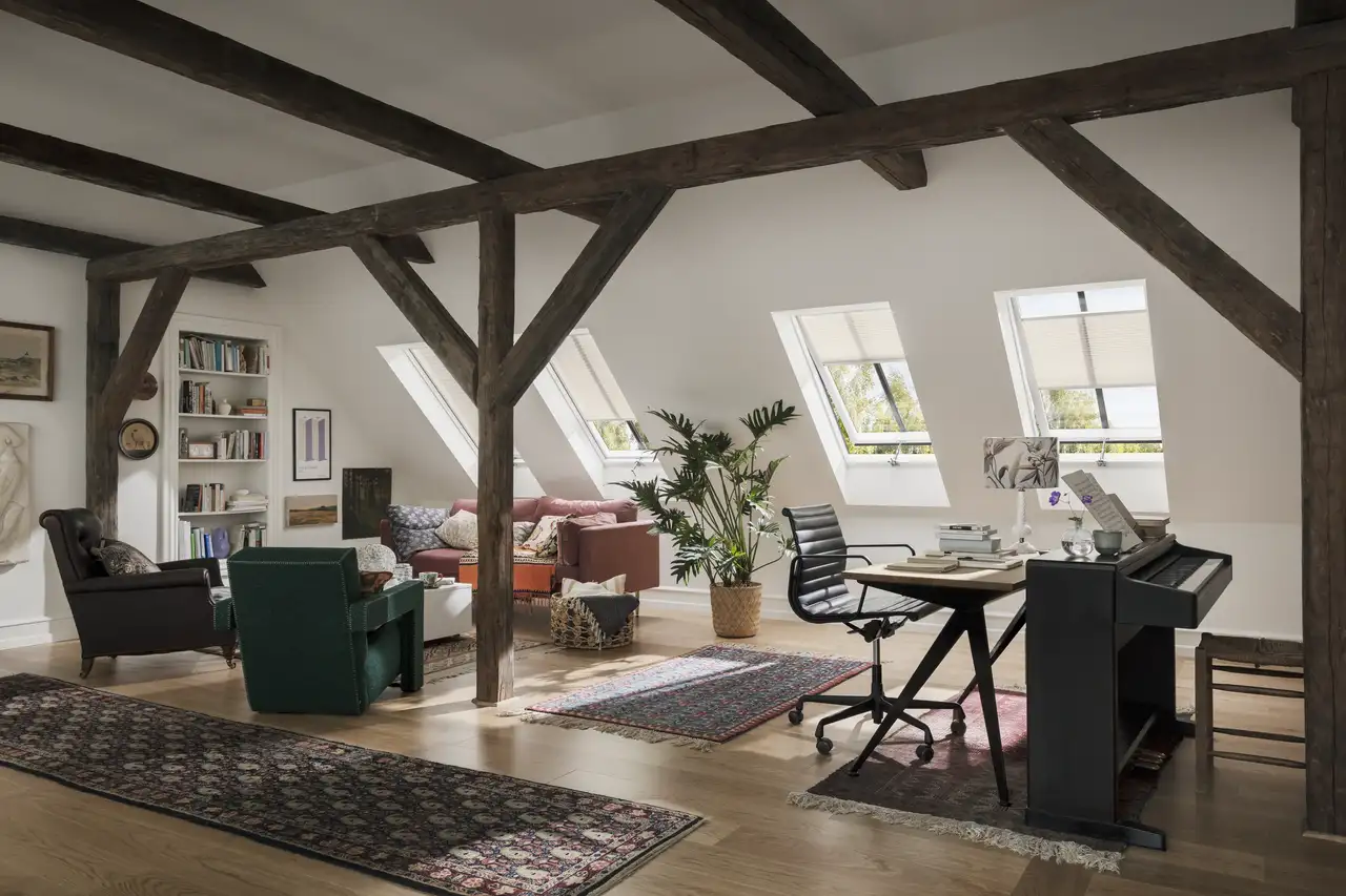 Quattro finestre per tetti VELUX illuminano zona soggiorno e home office in un open space.