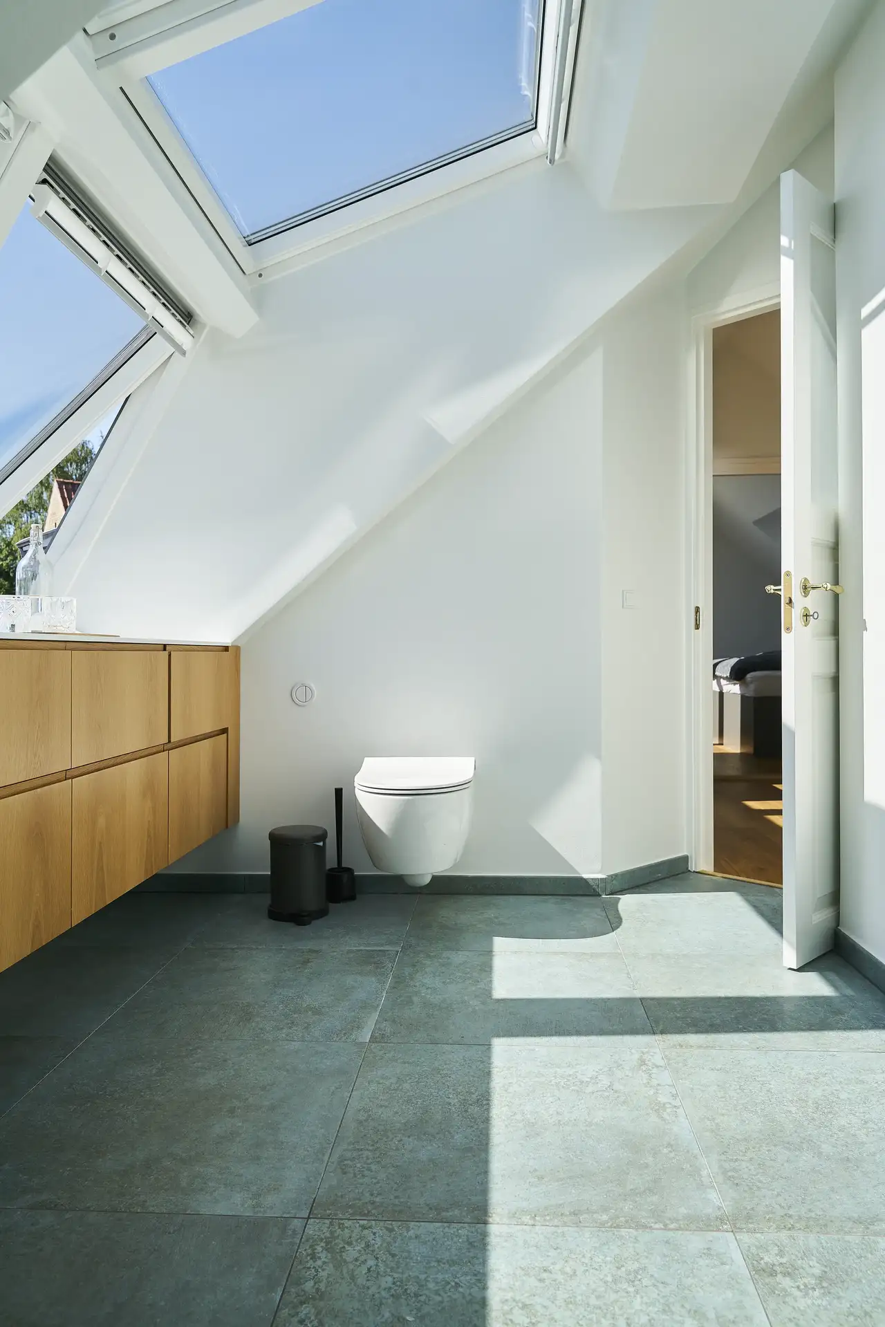 Bagno mansardato con finestra per tetti e sanitario installato sulla parete verticale. 