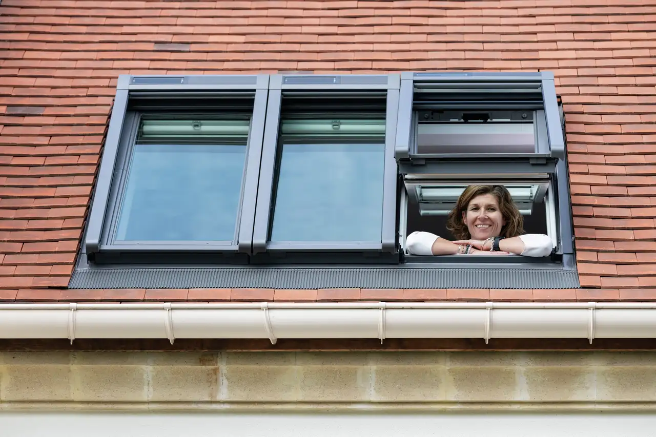 Een vrouw kijkt door een VELUX dakvenster.
