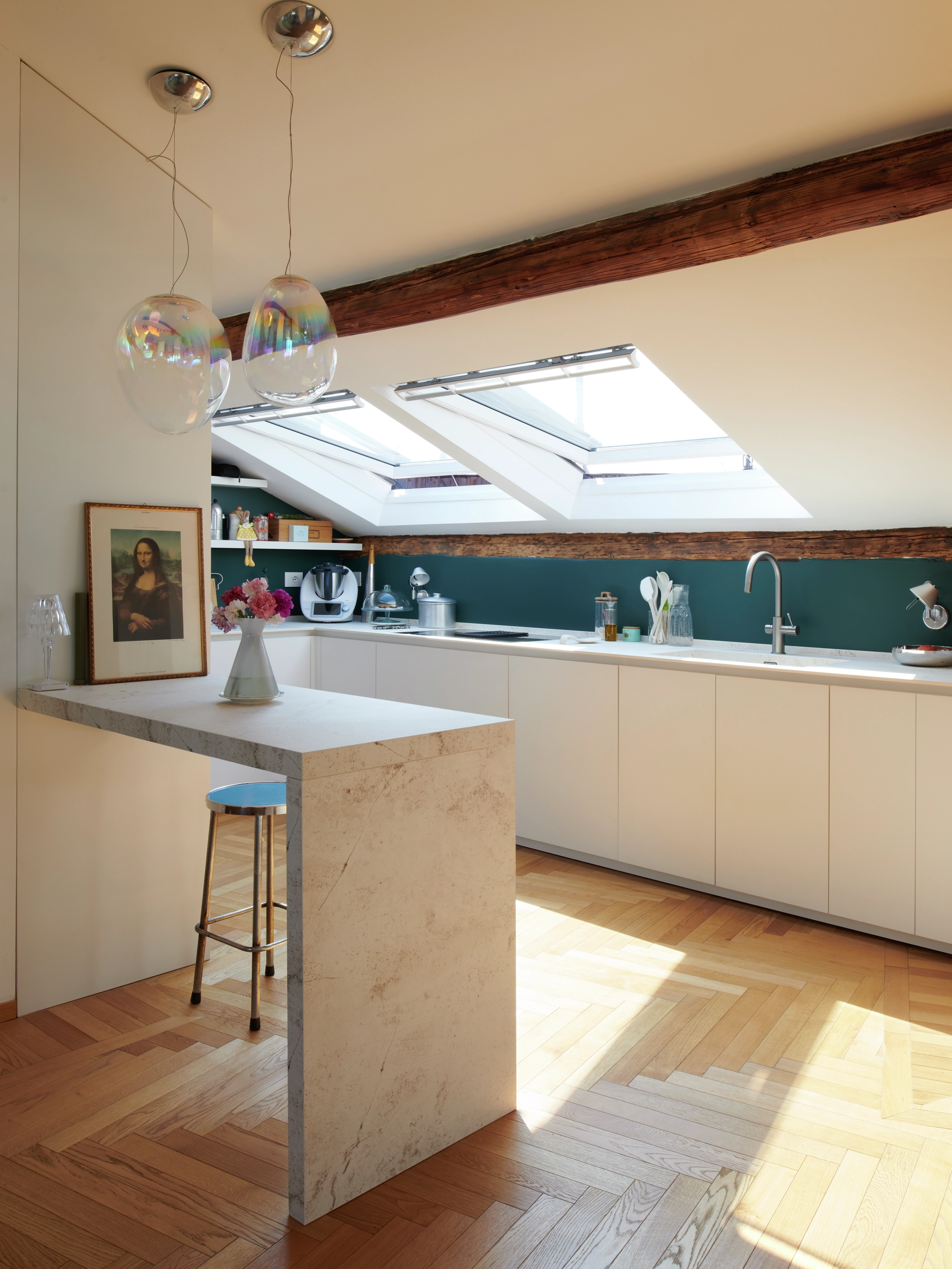 Cucina mansardata con soffitto inclinato, finestra per tetti aperta e design moderno.