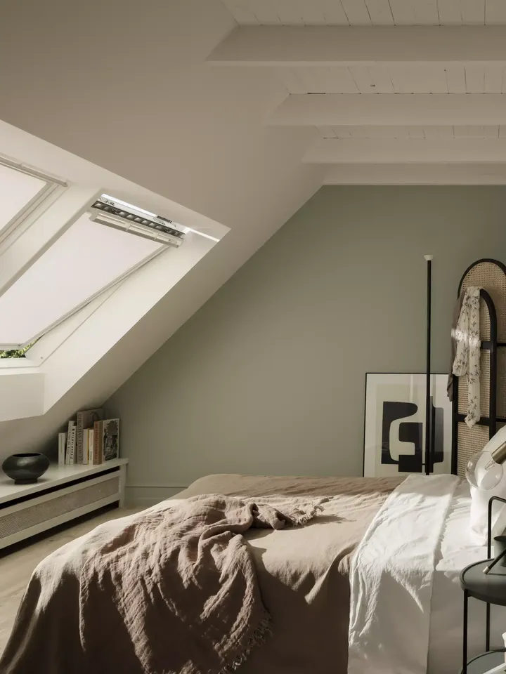 Gemütliches Dachboden-Schlafzimmer mit natürlichem Licht von VELUX Dachflächenfenstern und minimalistischer Dekoration.