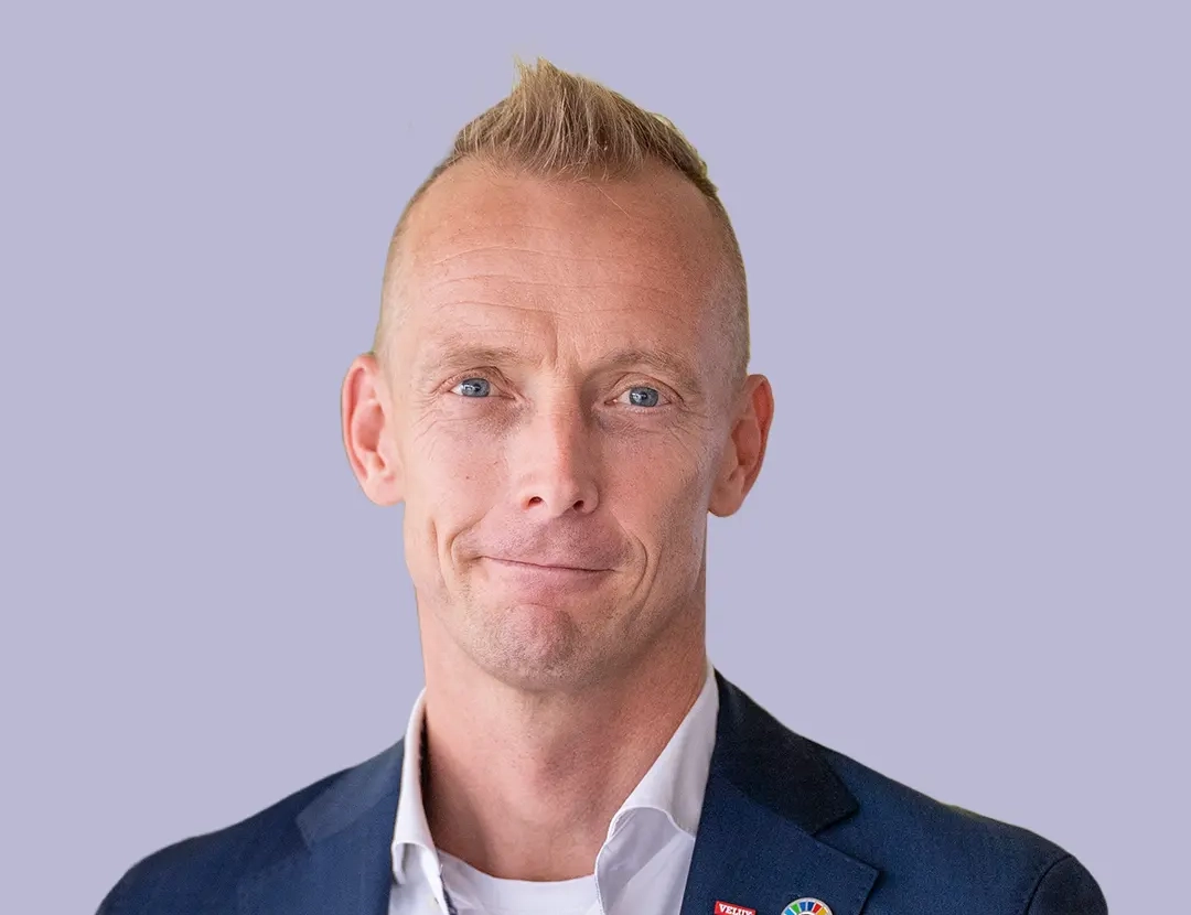 Person in navy suit with VELUX pin and colorful badge.