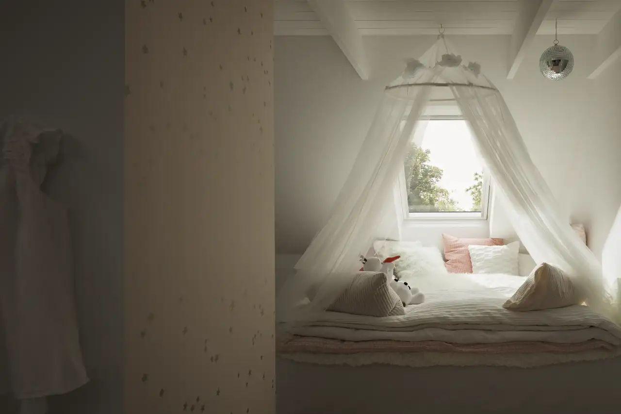 Chambre avec lit protégé par une moustiquaire à baldaquin sous une fenêtre de toit. 