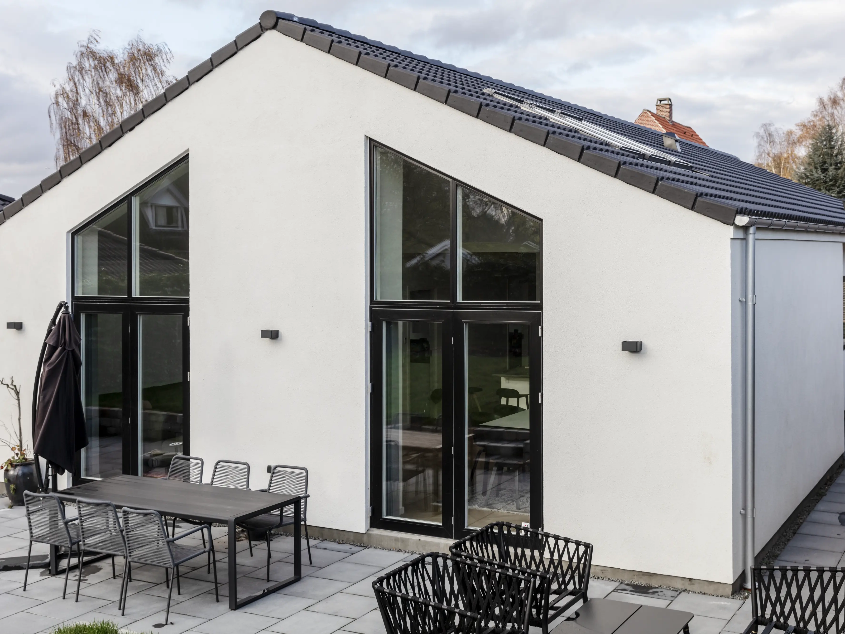 Casa con design moderno, tetto a falde con finestre per tetti VELUX e ampie finestre verticali.