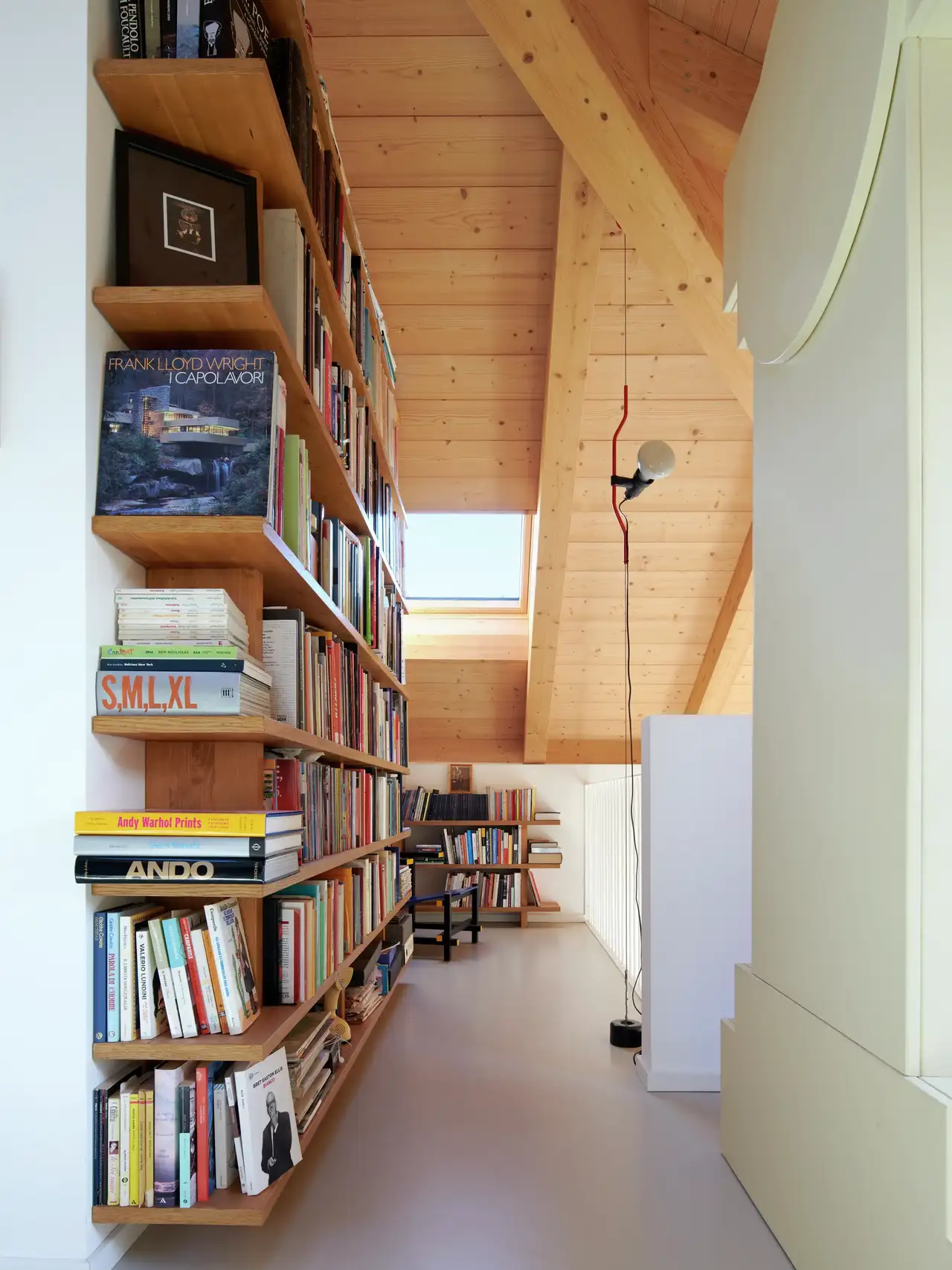 combles avec toit en bois, fenêtre de toit VELUX, lampe et bibliothèque