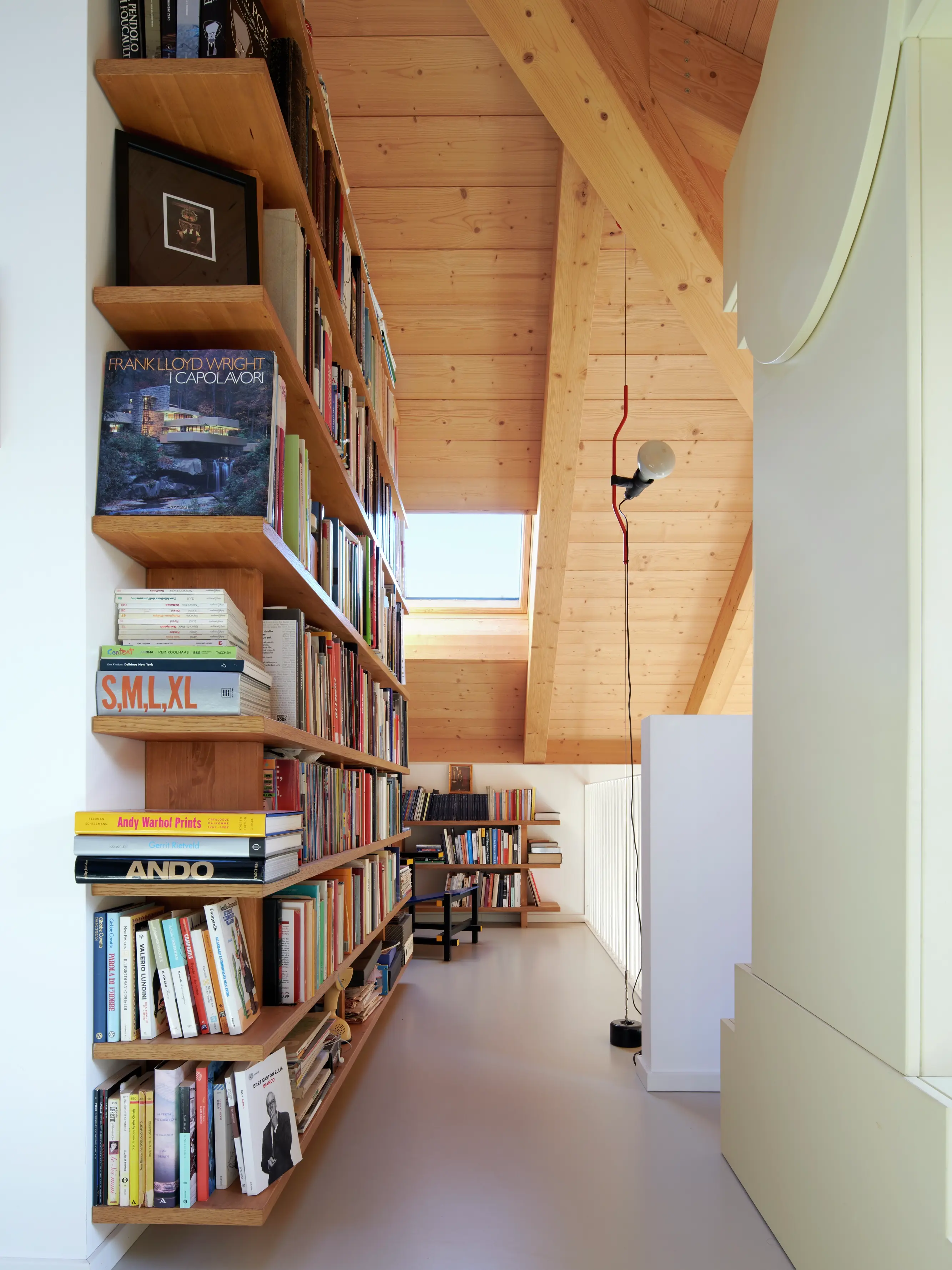 Espace de lecture dans le comble avec des étagères en bois et une fenêtre de toit VELUX.