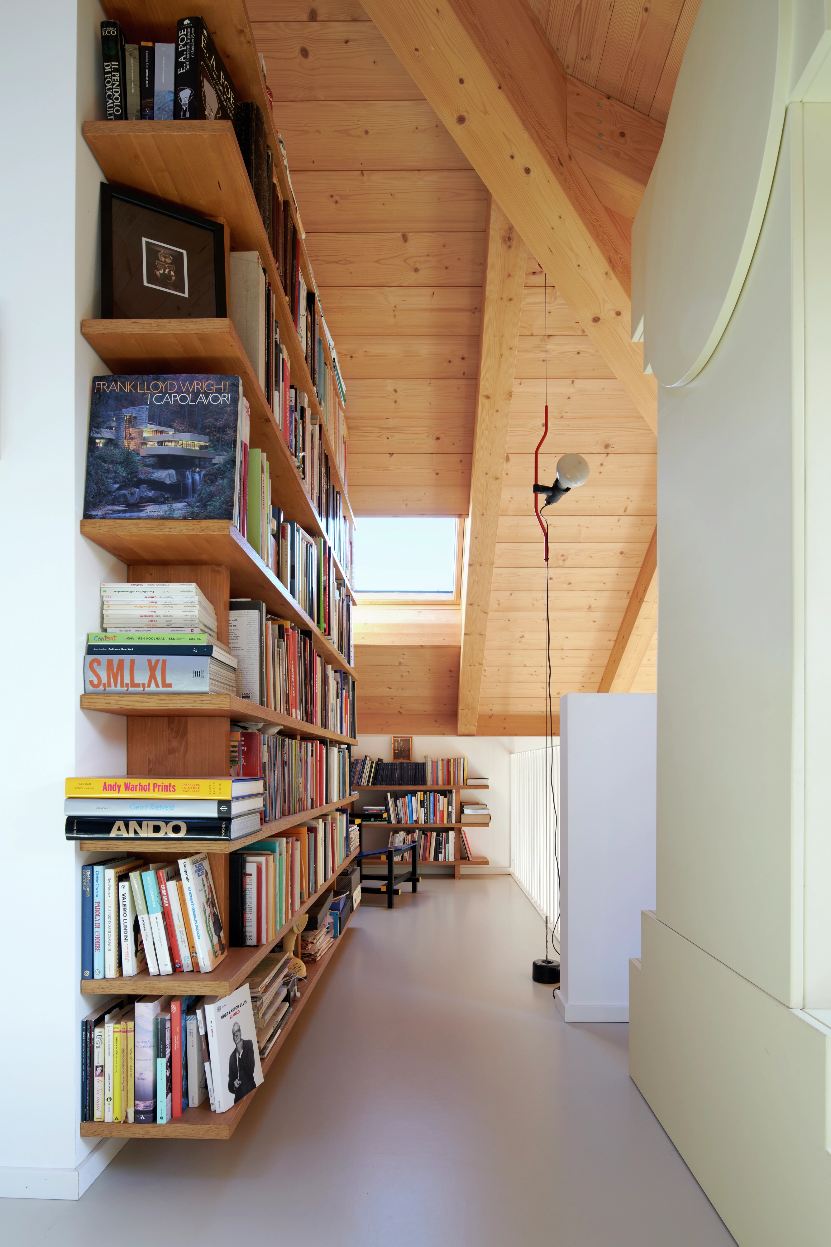 Espace de lecture dans le comble avec des étagères et une fenêtre de toit VELUX illuminant l'espace.