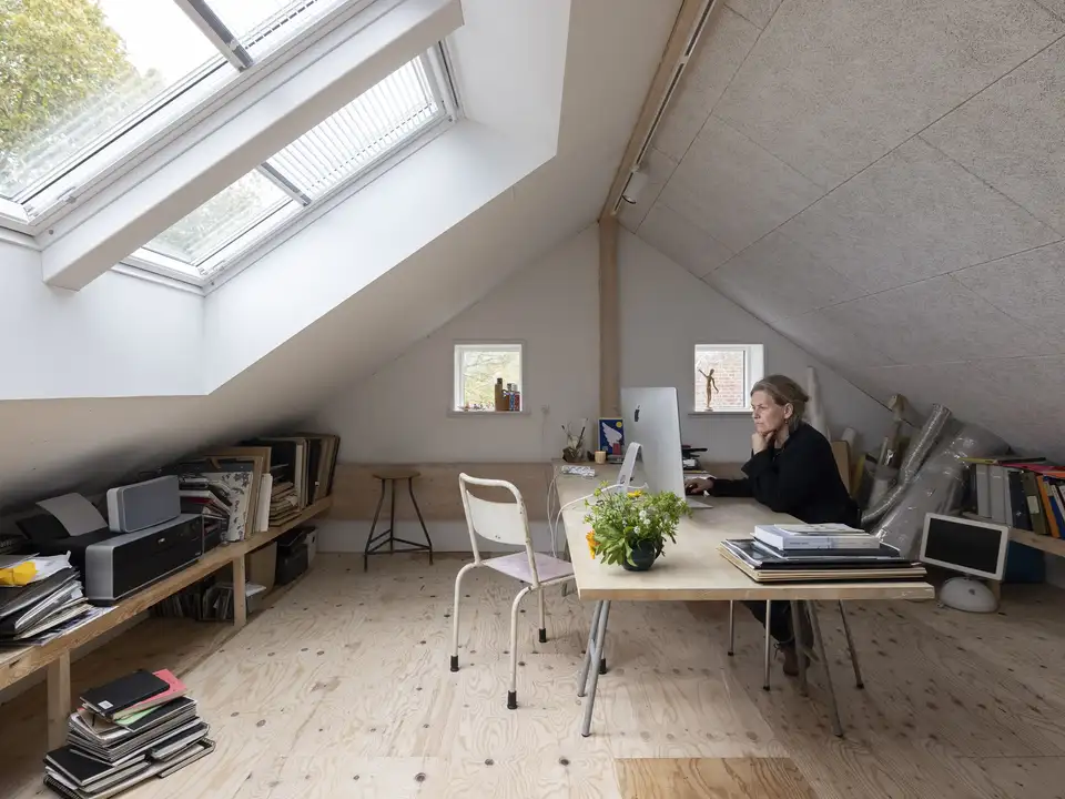bureau sous les toits installé sous deux fenêtres de toit VELUX équipées de stores vénitiens partiellement ouverts