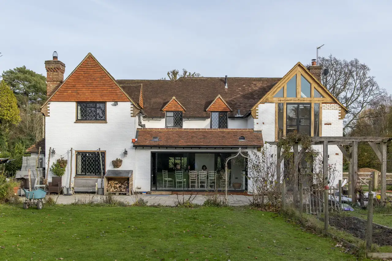 Countryside house with white brick facade and red tile roof, large windows