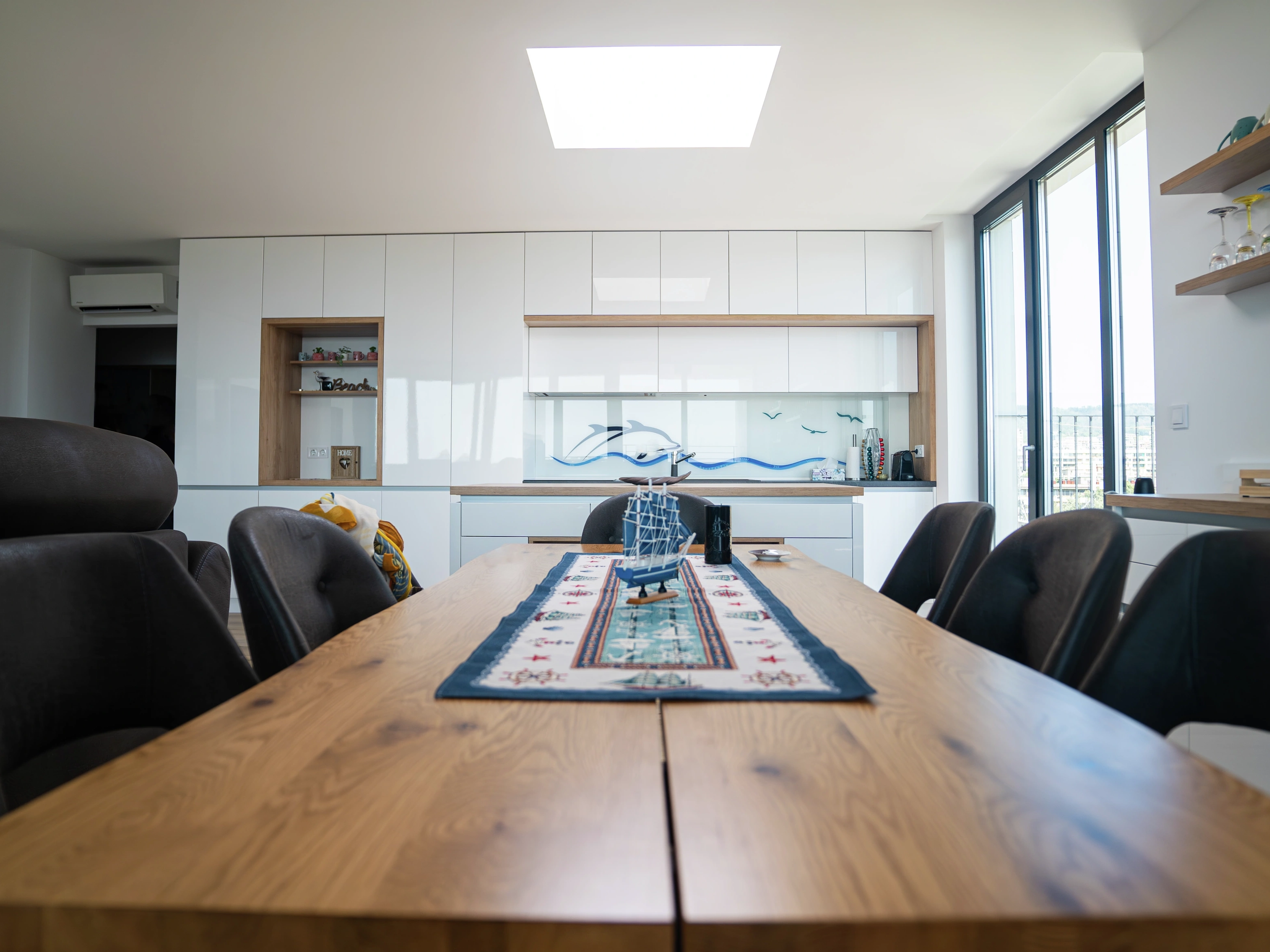 Modern dining room with VELUX flat roof window above wooden table.
