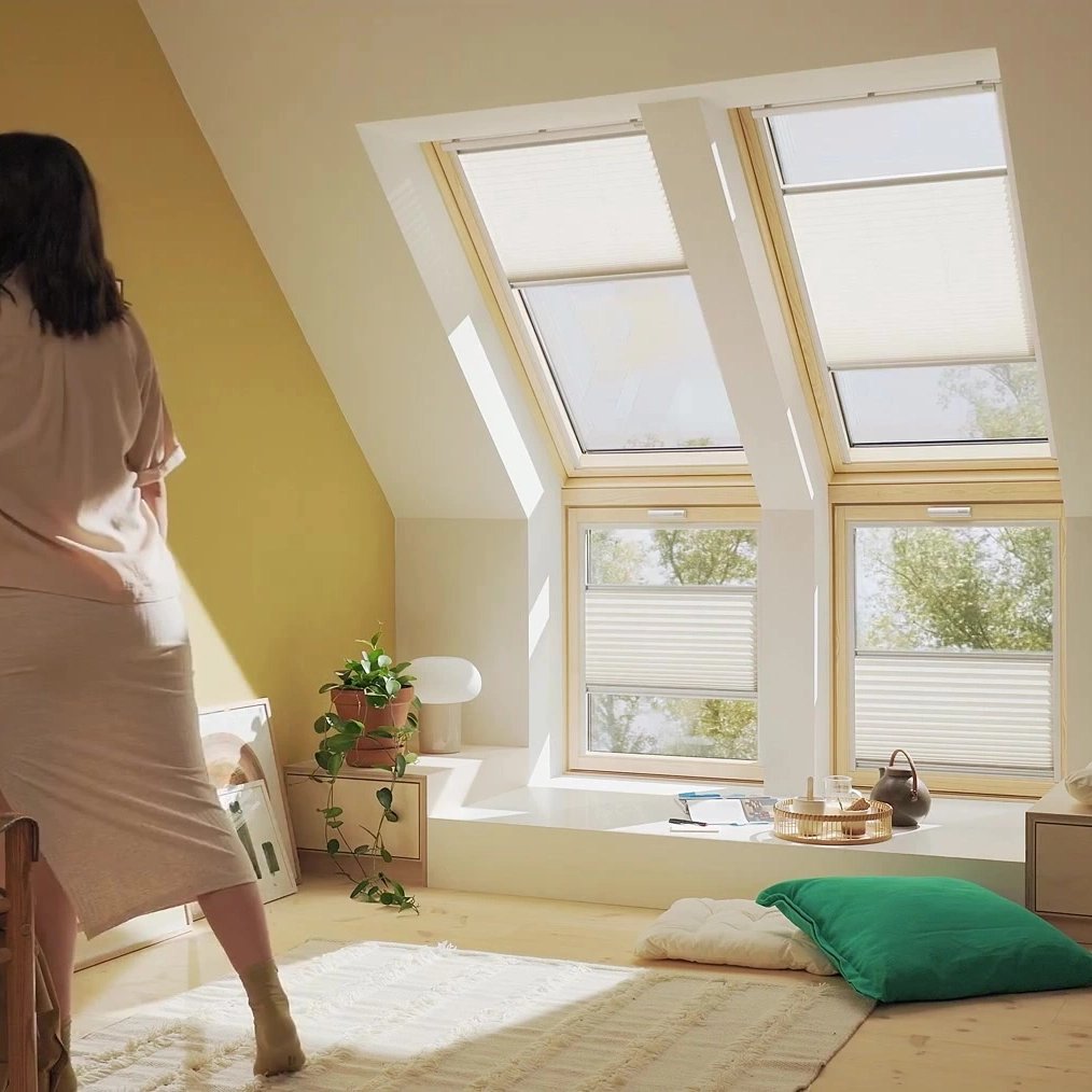 Woman painting in a sunlit room with VELUX roof windows.