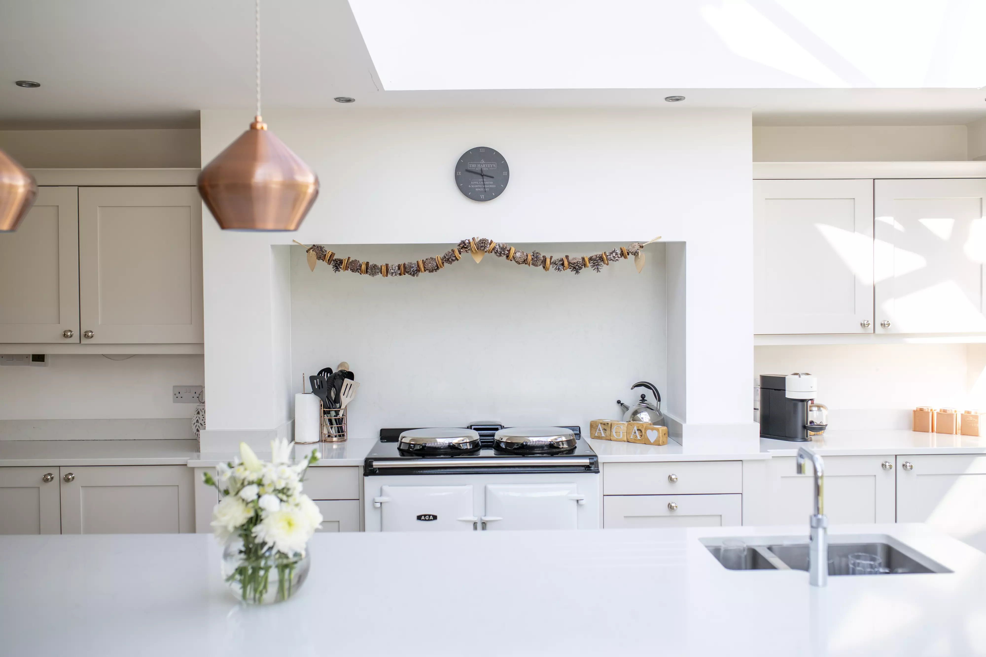 Modern kitchen with white cupboards, VELUX roof window, and copper lights.