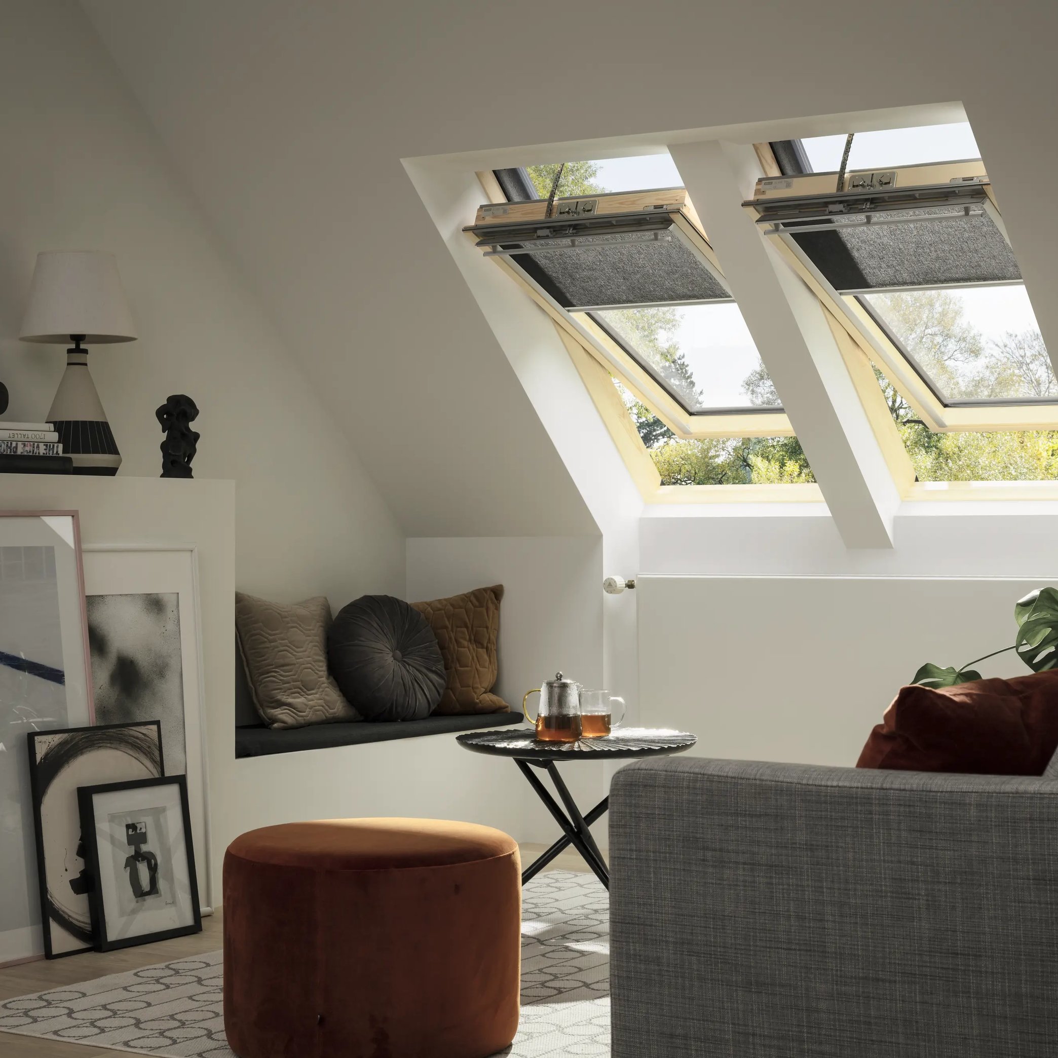Attic living space with VELUX roof windows, sofa, and art pieces.