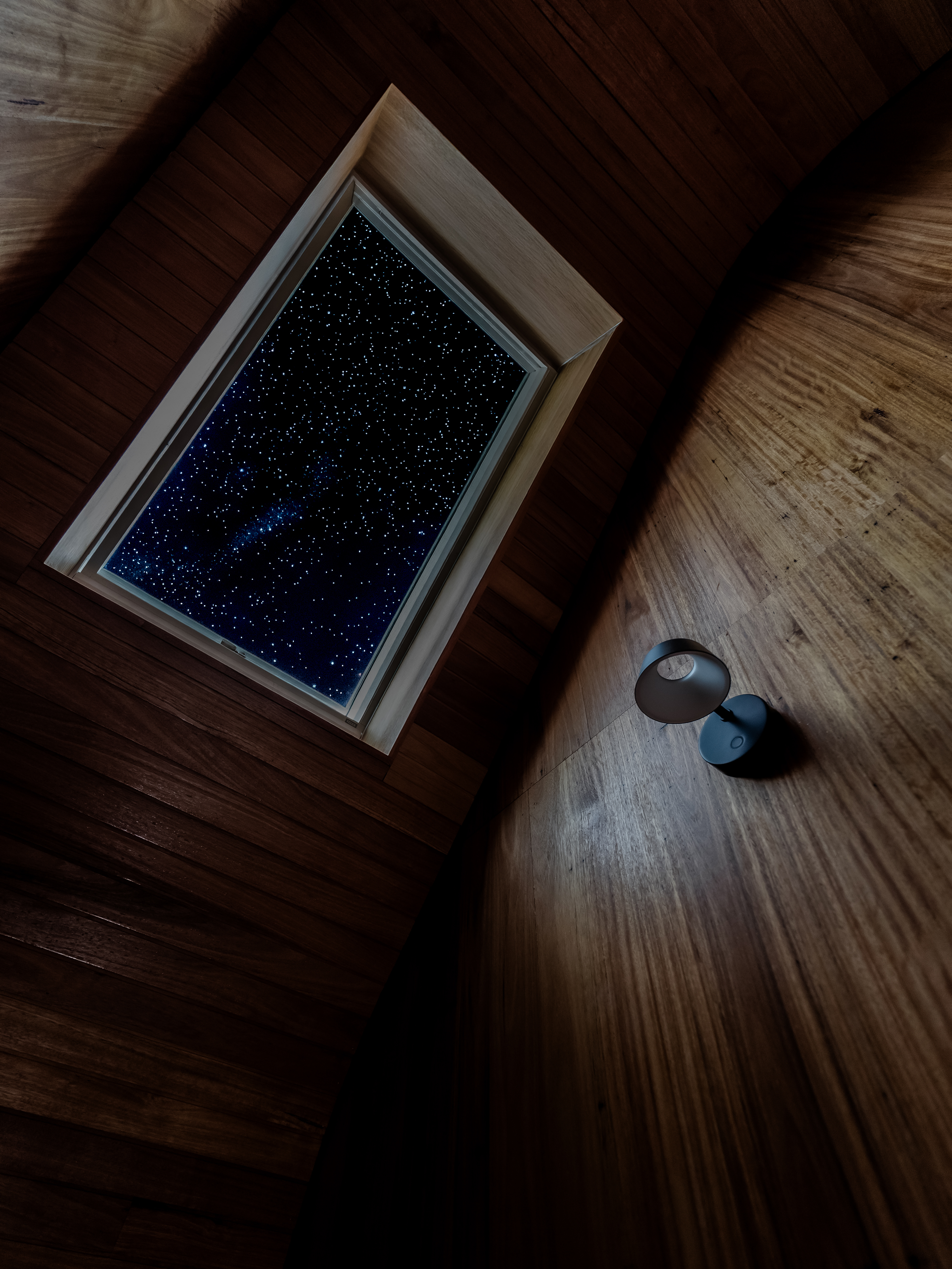 Wood-clad attic with VELUX roof window showing a clear, starry night sky.