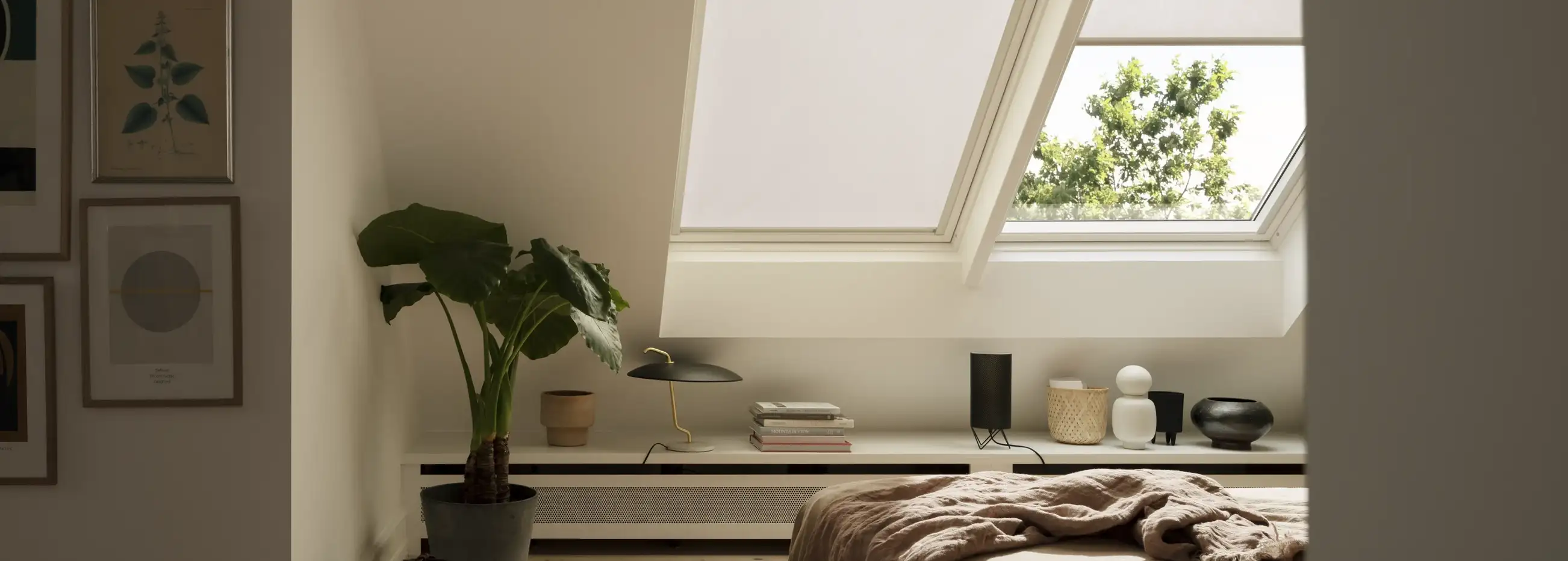 Attic bedroom with sloped ceiling and VELUX roof window, natural light entering.