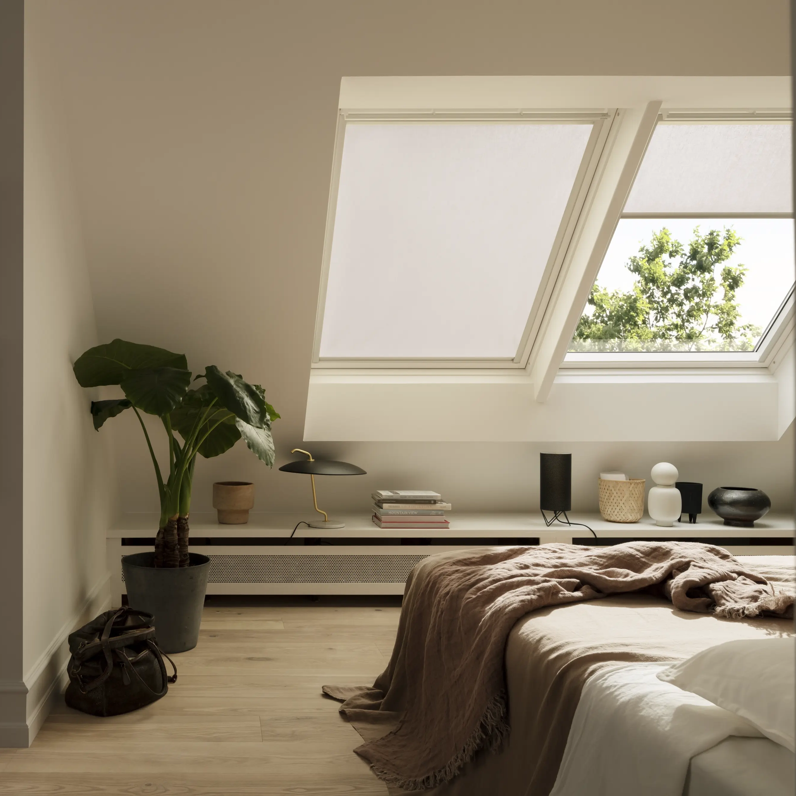 Attic bedroom with sloped ceiling and VELUX roof window, natural light entering.
