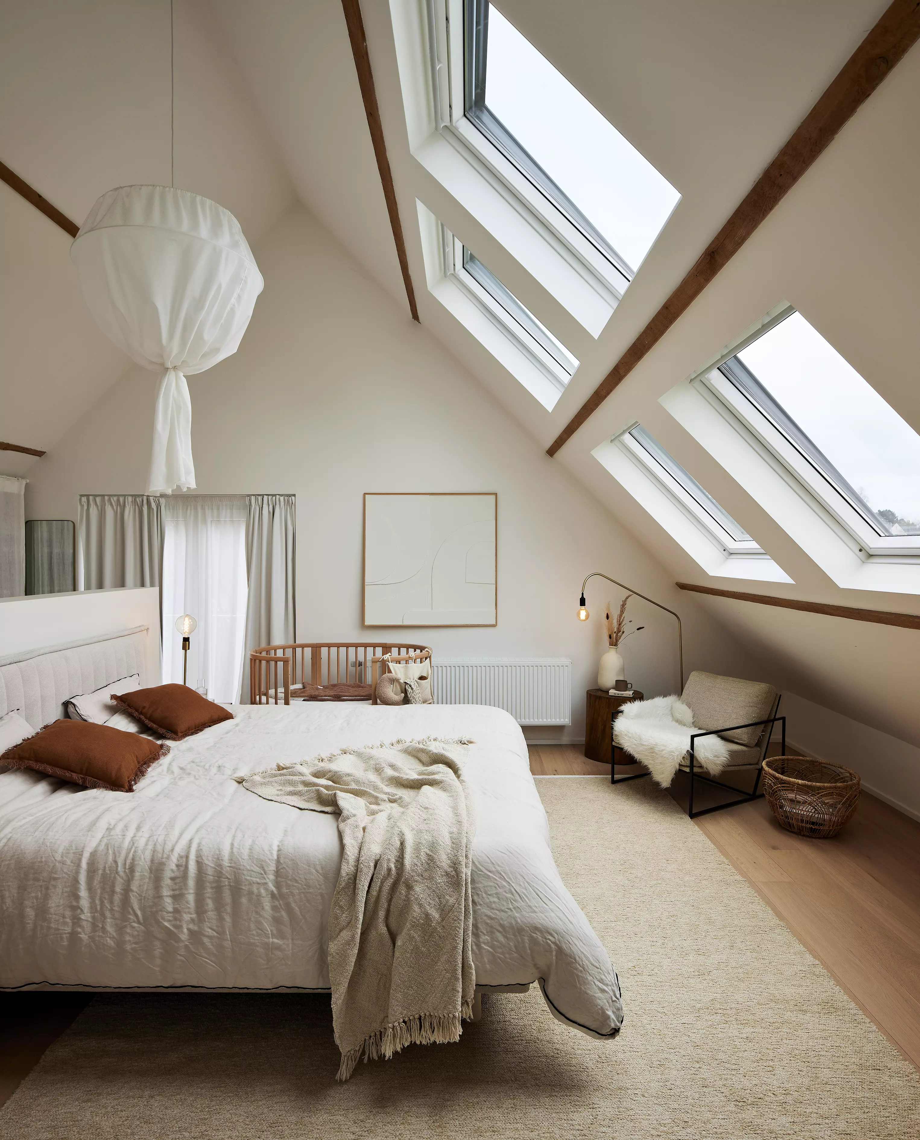 Chambre mansardée confortable avec literie douillette, poutres en bois et fenêtres de toit VELUX.