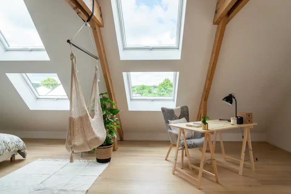 Pièce mansardée lumineuse avec parquet clair et grandes fenêtres de toit