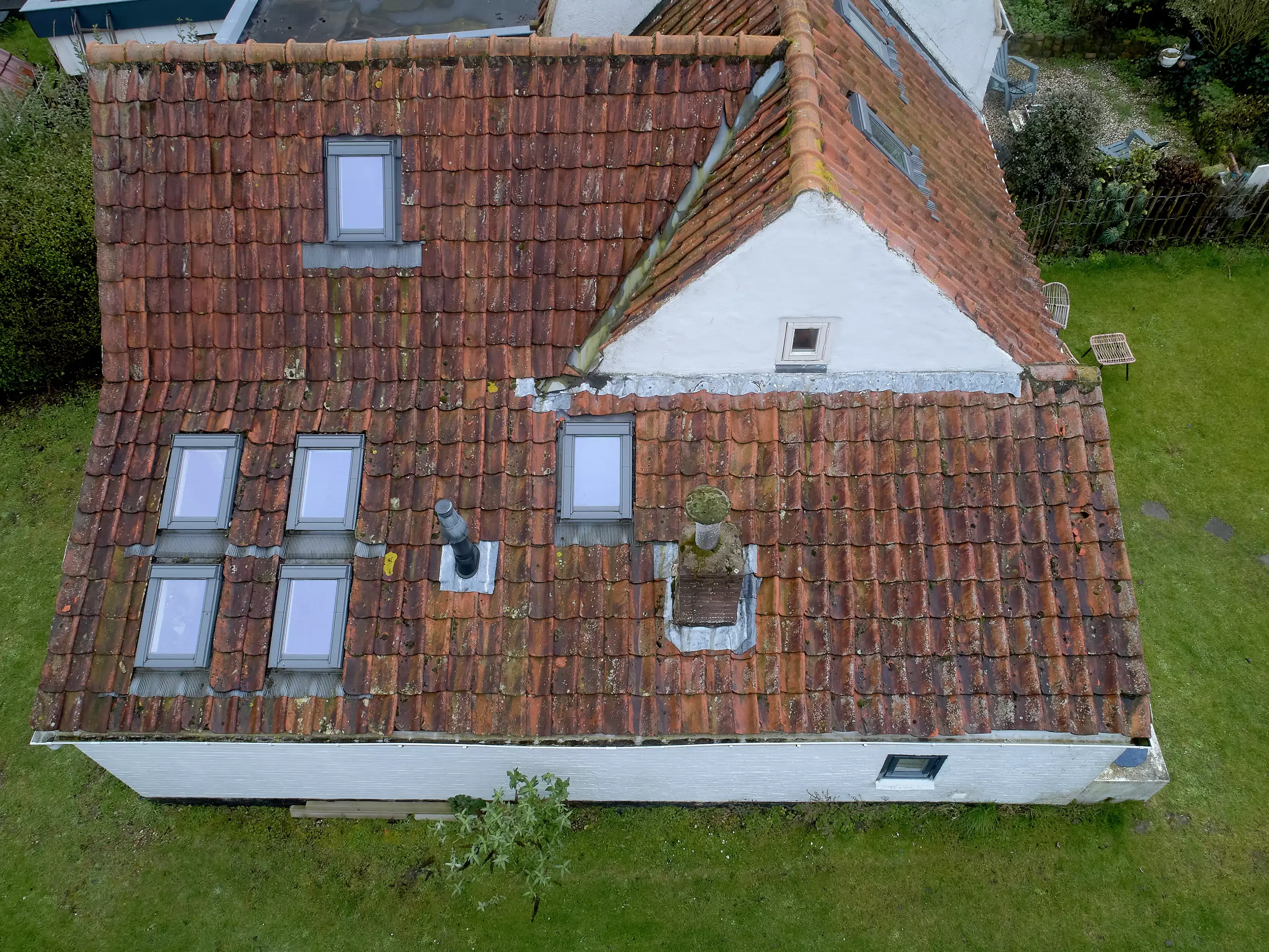 Vue aérienne d'une maison rustique avec des tuiles rouges et des fenêtres de toit VELUX.