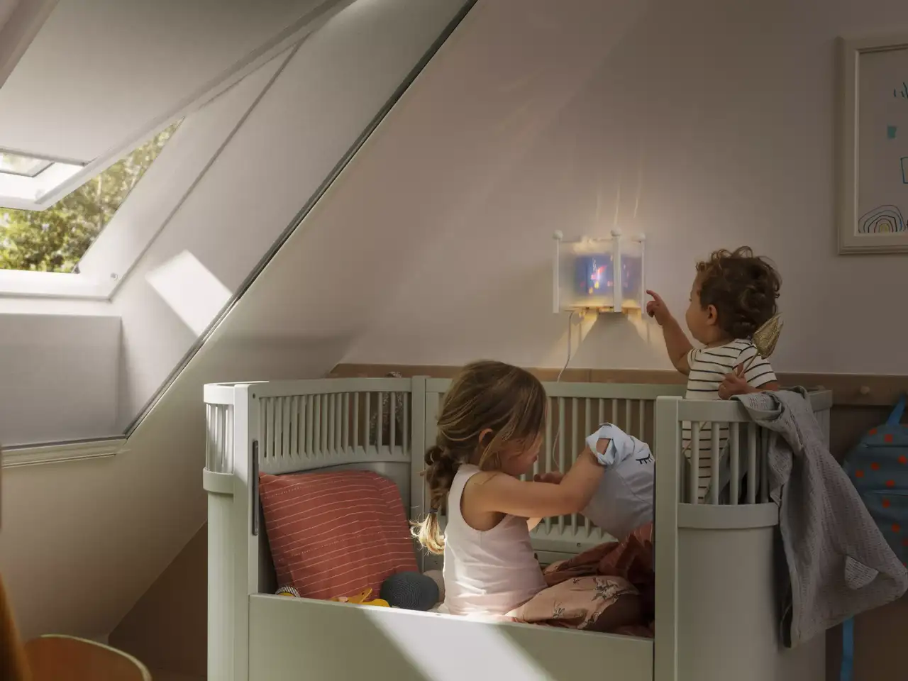Attic kids room with sloped ceiling, VELUX roof window, children playing.