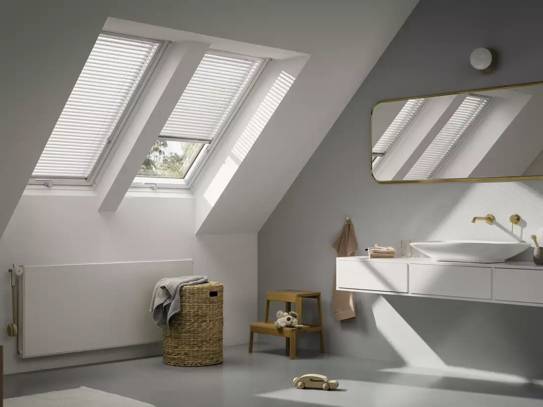 Attic bathroom with sloped ceiling and VELUX roof windows, modern design.