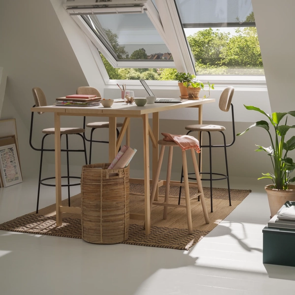 Attic workspace with sloped ceiling and VELUX roof windows, and awning blind, natural light entering and fresh air.