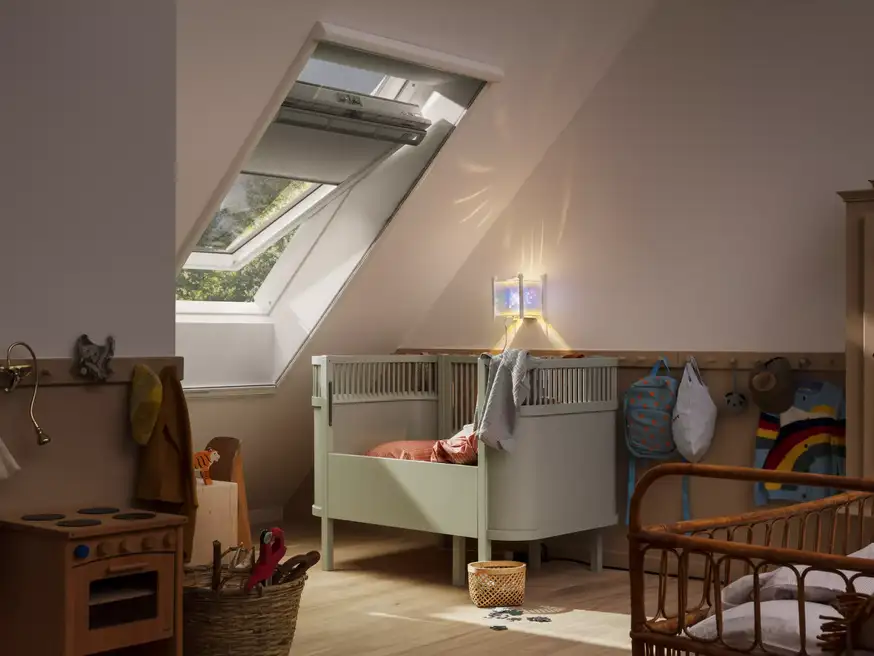 Attic kids room with sloped ceiling and VELUX roof window, cozy decor.