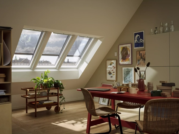 Attic workspace with sloped ceiling and VELUX roof windows, filled with natural light.